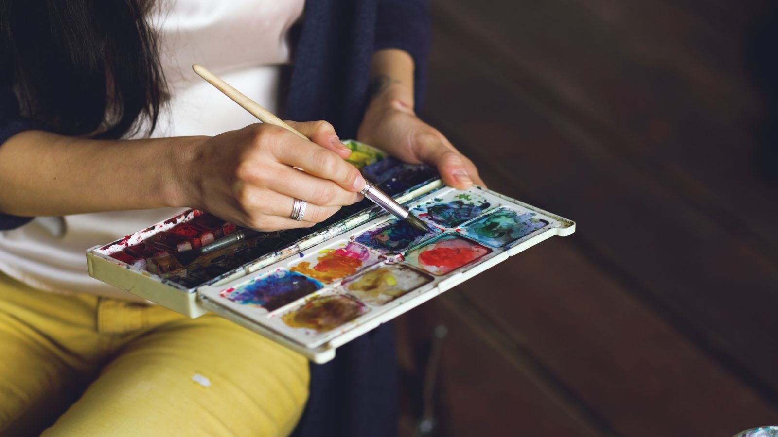 Close-up of a painter mixing colour on a palette in the workshop